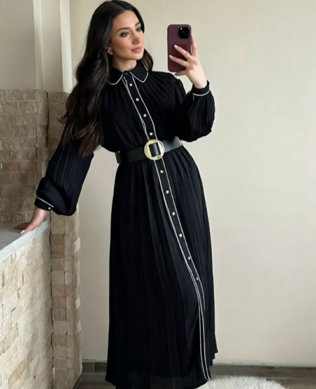Robe longue plissée noire avec finitions blanches et ceinture.
