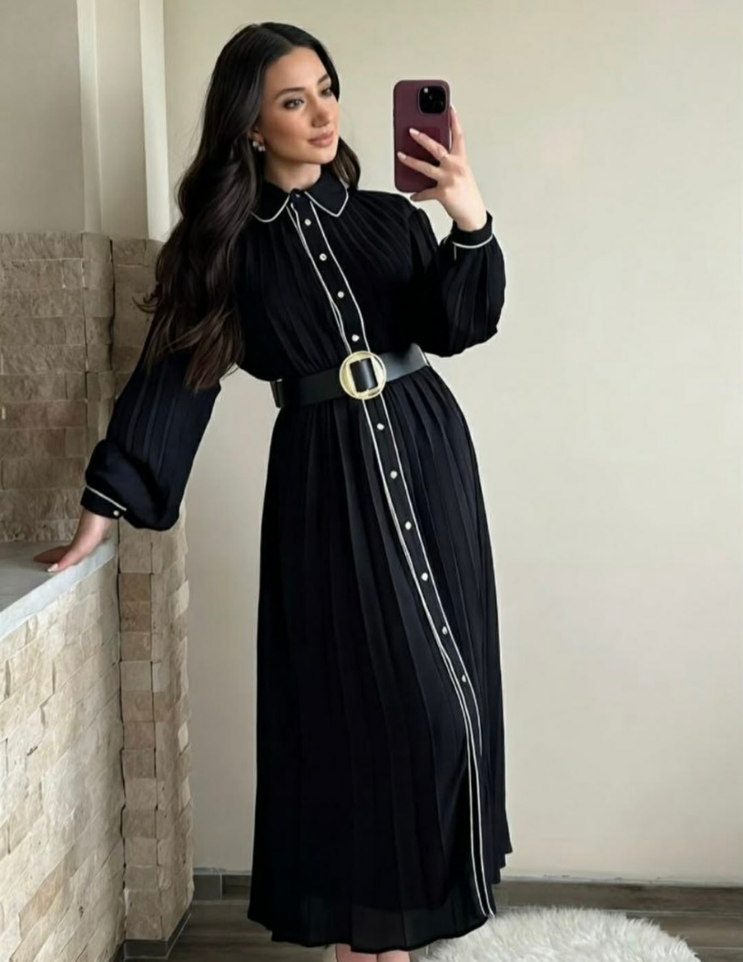 Robe longue plissée noire avec finitions blanches et ceinture.