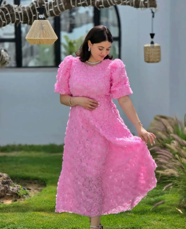 Robe midi rose à manches bouffantes et détails floraux en relief.