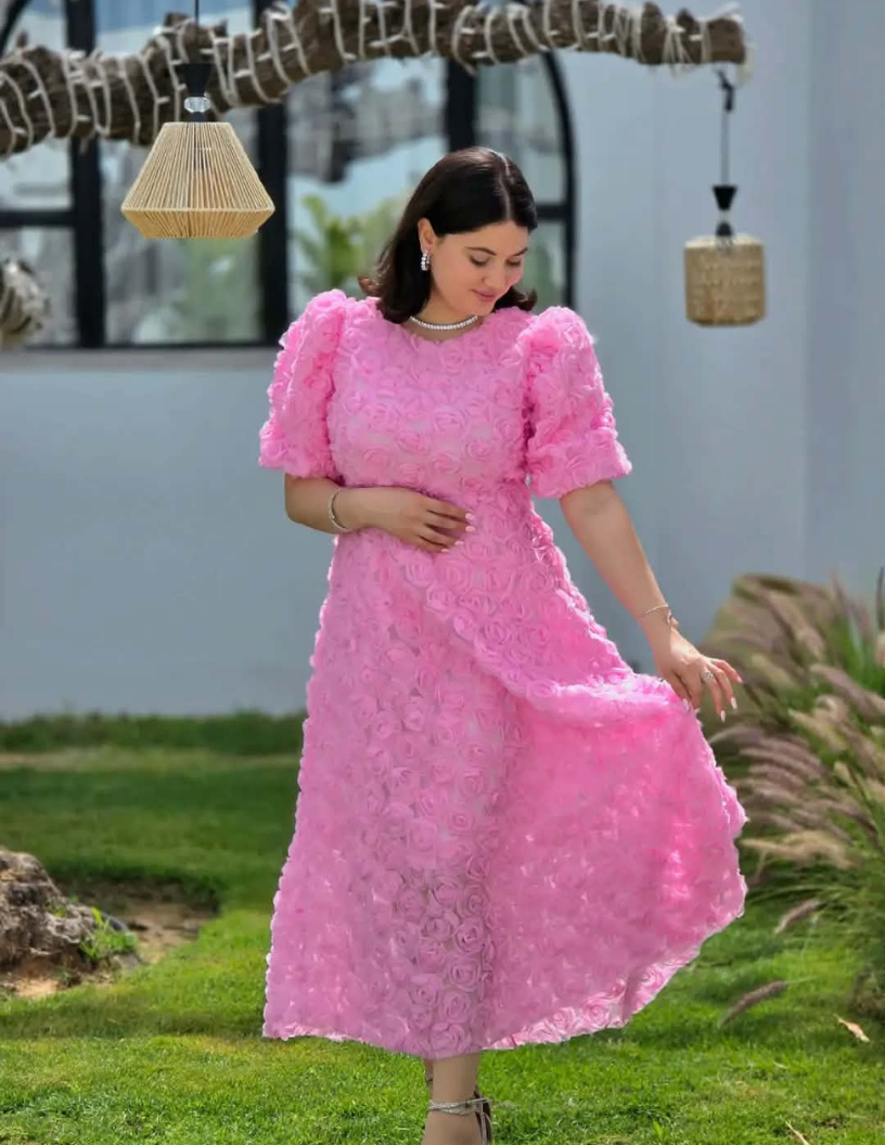 Robe midi rose à manches bouffantes et détails floraux en relief.
